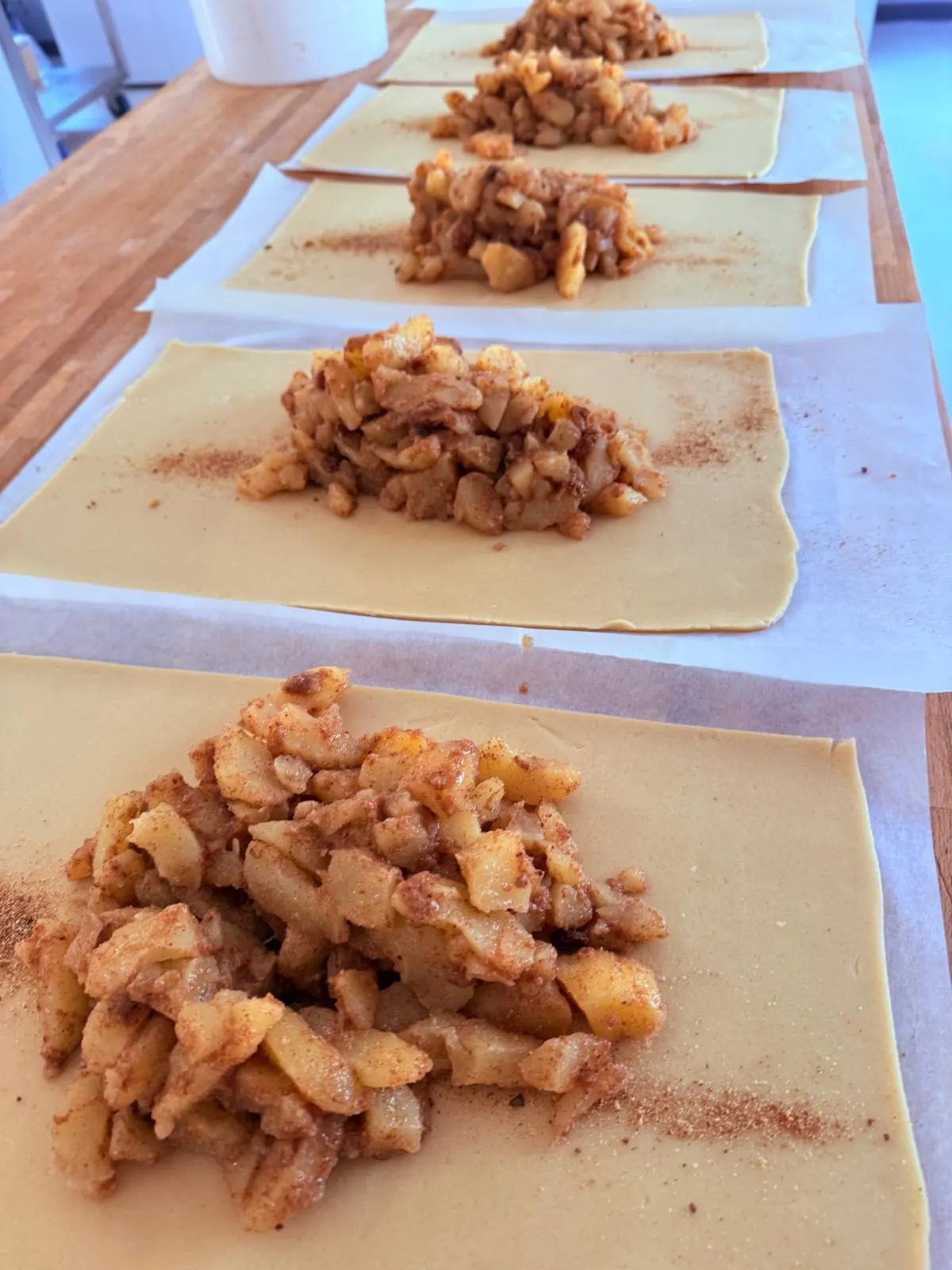 Ausgerollter Strudelteig mit Apfelfüllung und Zimt auf dem Arbeitstisch
