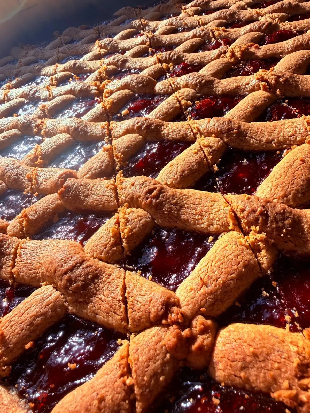 Linzer vom Blech mit Teiggitter und roter Marmelade, in Stücke geschnitten