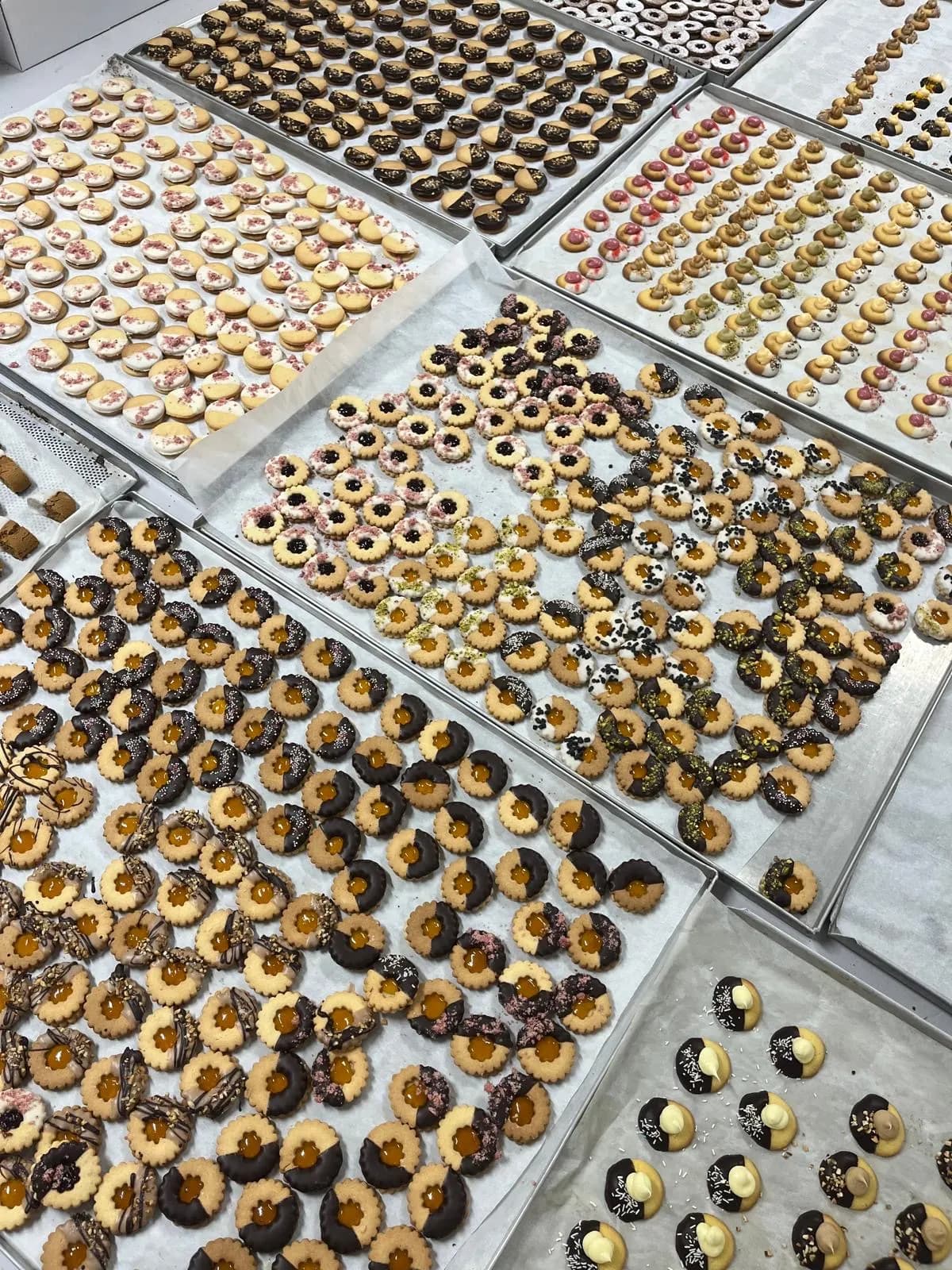 Backbleche voller Kekse in der Backstube: Linzer Augen, Schokokekse und Kekse mit Pistazien
