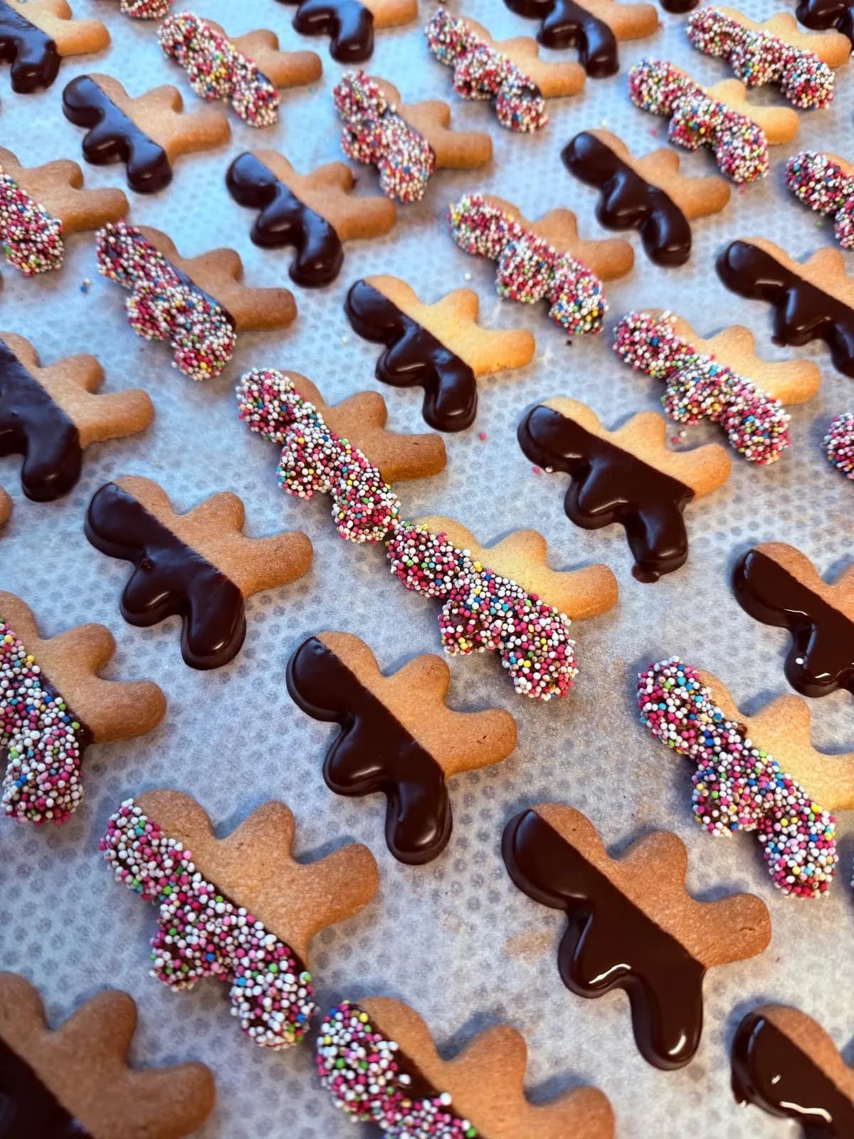 Kekse in Form von Rentiergeweihen, halb in Schokolade getaucht oder mit bunten Zuckerperlen