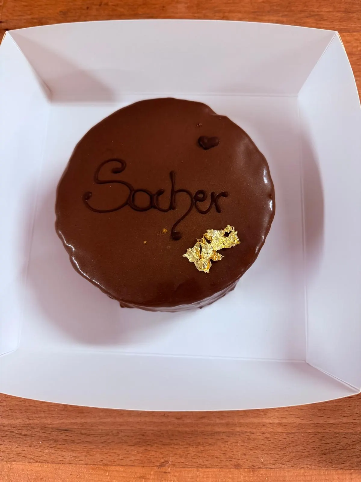 Sacher-Törtchen von oben, mit Schokoladenglasur, Schriftzug „Sacher“ und Blattgold