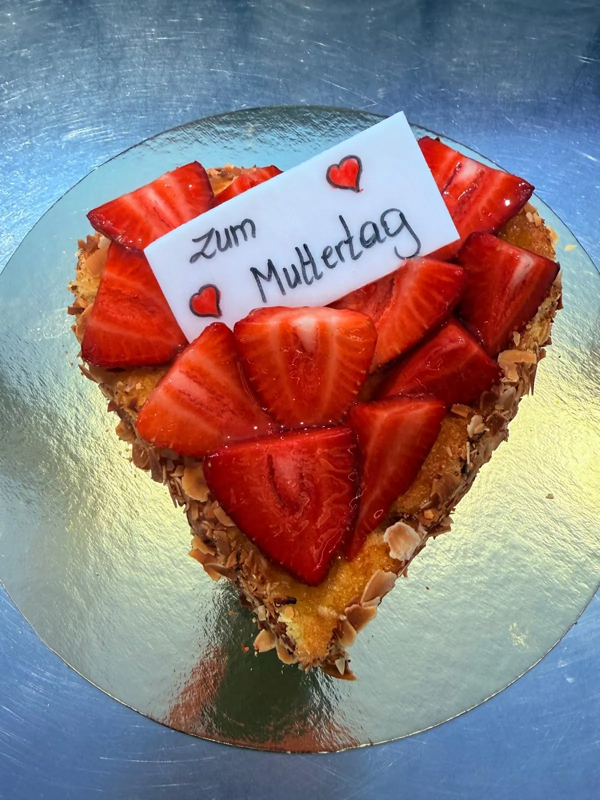 Herztorte mit Erdbeeren, Mandelrand und dem Schild „Zum Muttertag“