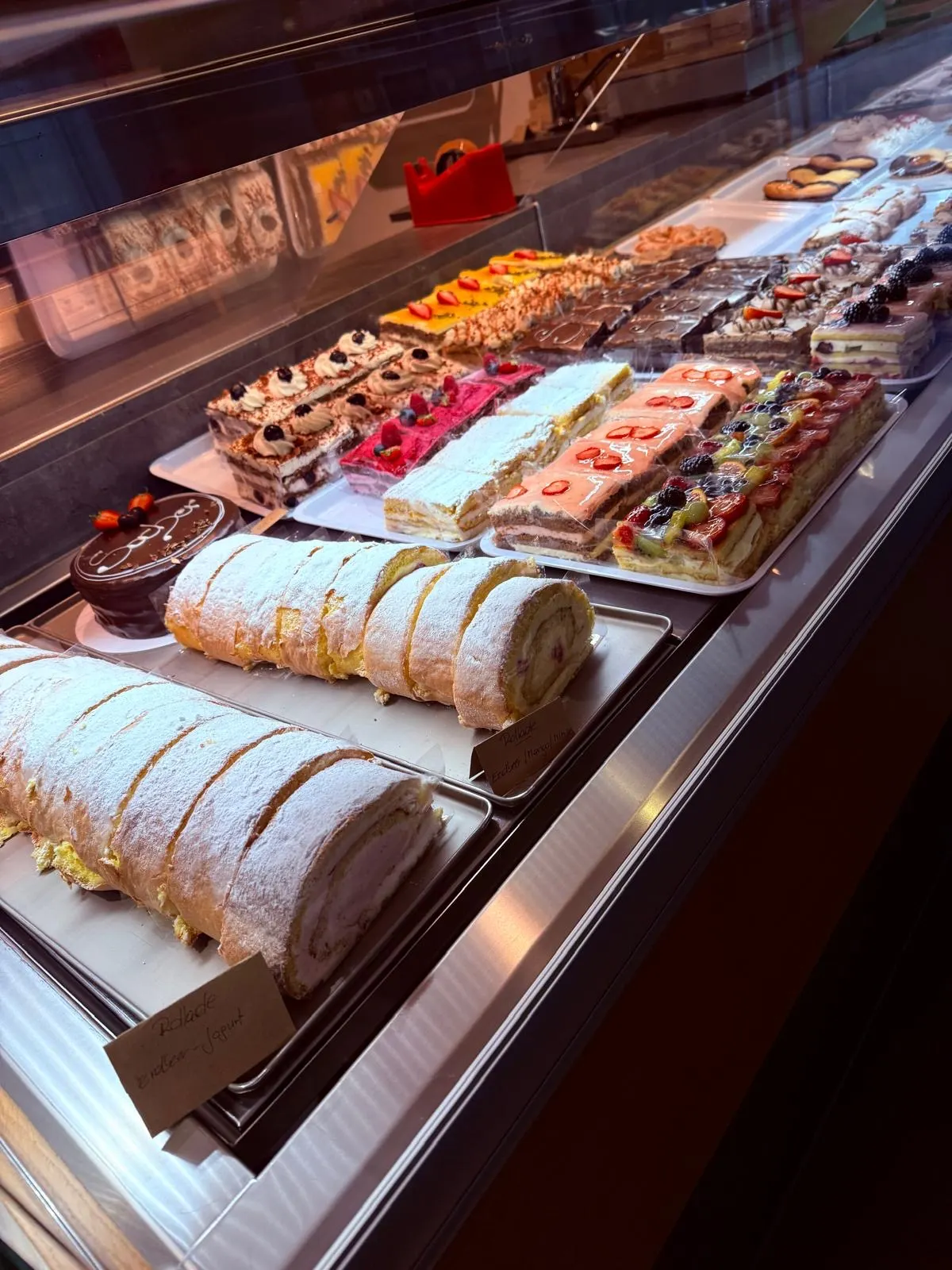 Kuchenvitrine mit Schnitten, Biskuitrollen und Torten